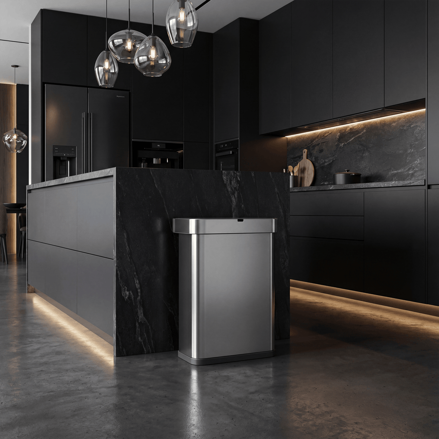 Simplehuman's 58L Sensor Can in Brushed in a dark, modern styled kitchen with black cabinets and marble countertop surrounded by ambient lighting and sleek touch.
